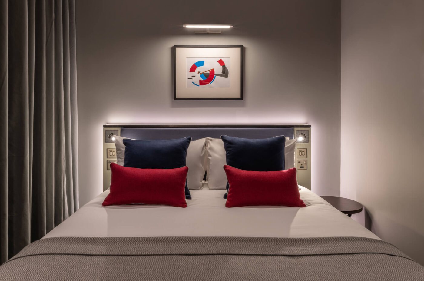 Double bed with colourful pillows, and artwork placed above the bed.