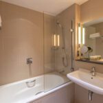 A bathroom with a built in bathtub and shower, with towel racks.