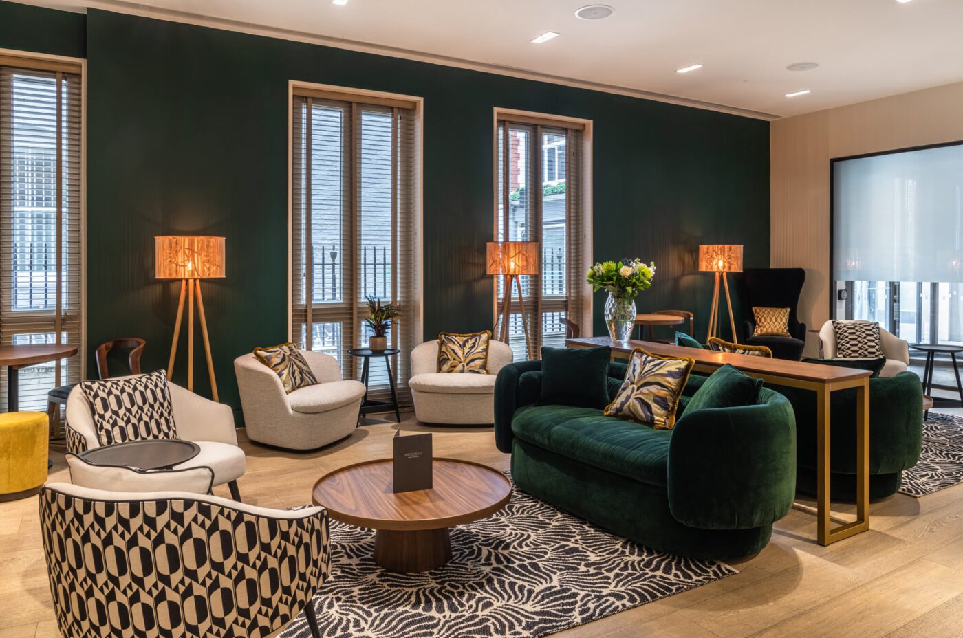 A hotel lounge with sofas, a coffee table and lamps.