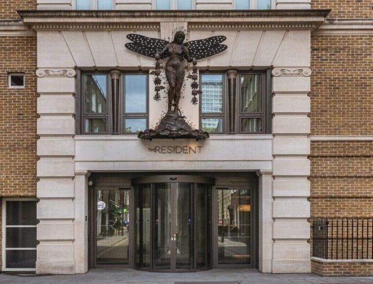 The entrance to a brick building with a large butterfly sculpture above the door and the word 